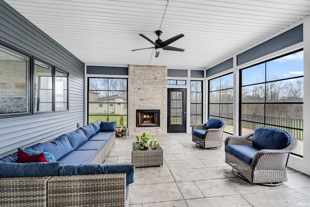 sunroom / solarium with a stone fireplace, ceiling fan, and wooden ceiling