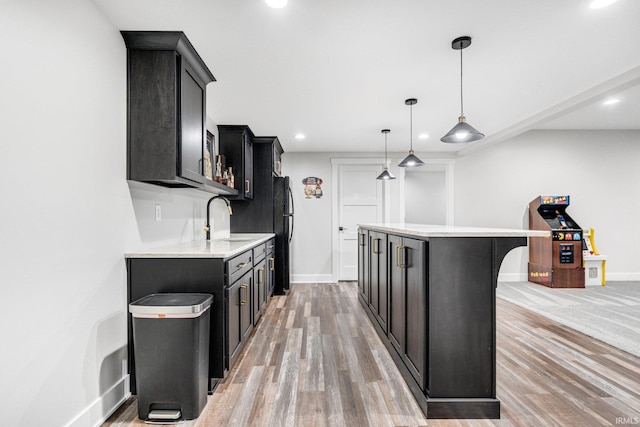 kitchen with sink, light hardwood / wood-style flooring, decorative light fixtures, a kitchen island, and a breakfast bar area