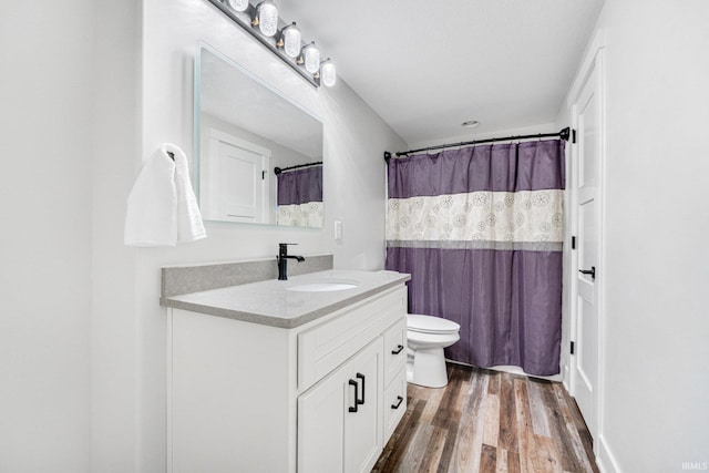 bathroom with hardwood / wood-style flooring, vanity, curtained shower, and toilet