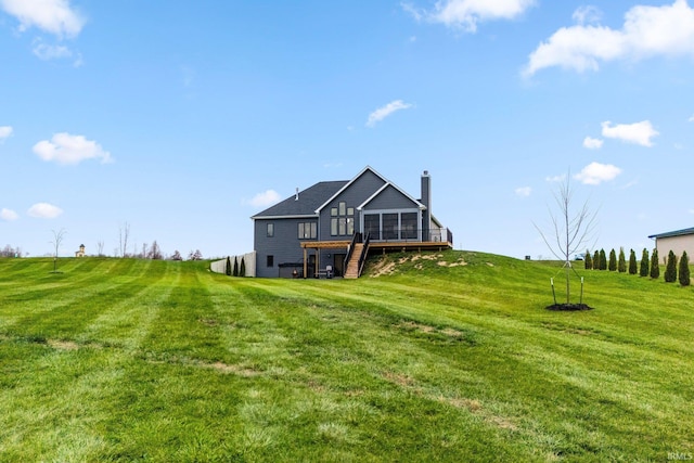 back of house featuring a lawn, a sunroom, a rural view, and a wooden deck