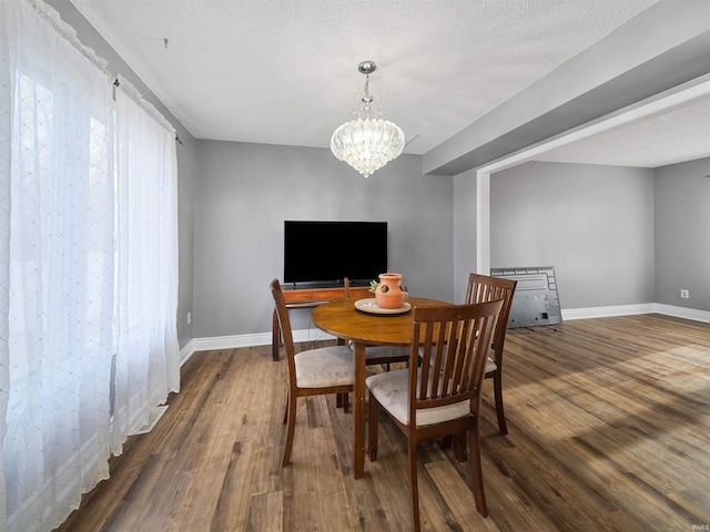 dining area with a textured ceiling, an inviting chandelier, and dark wood-type flooring