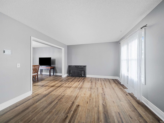 unfurnished living room with wood-type flooring and a textured ceiling