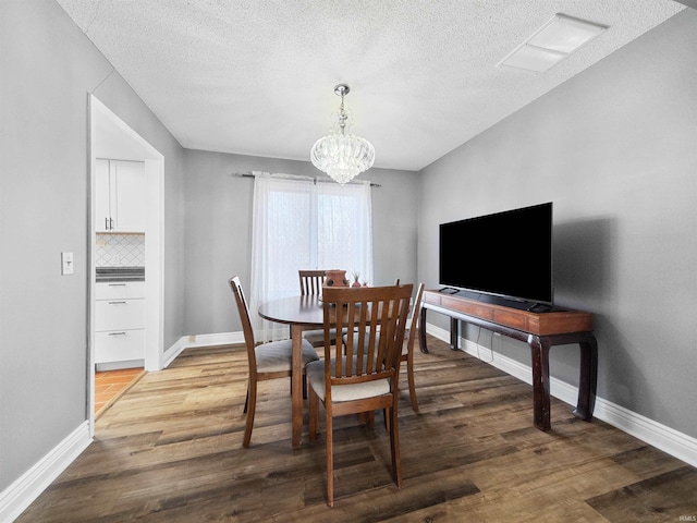 dining area with a textured ceiling, a notable chandelier, and hardwood / wood-style flooring