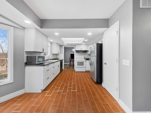 kitchen with wood-type flooring, white cabinetry, sink, and appliances with stainless steel finishes