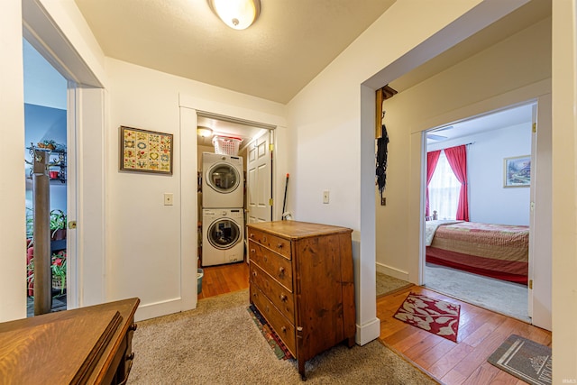 laundry room with stacked washer / drying machine and light wood-type flooring