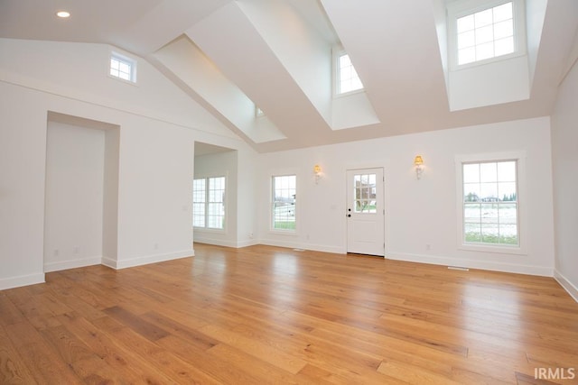 unfurnished living room featuring light hardwood / wood-style floors and high vaulted ceiling