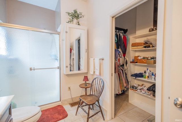 bathroom with tile patterned floors, toilet, and a shower with door