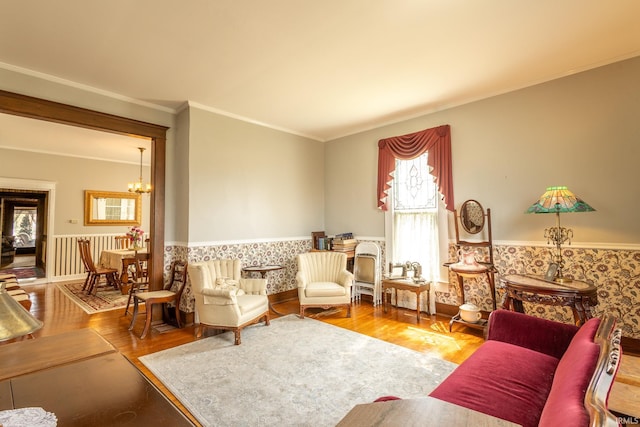 sitting room with hardwood / wood-style floors, ornamental molding, and a notable chandelier