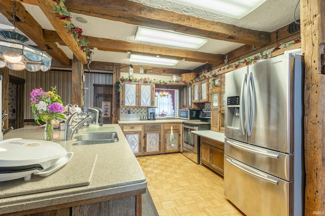 kitchen featuring beamed ceiling, sink, appliances with stainless steel finishes, and light parquet floors