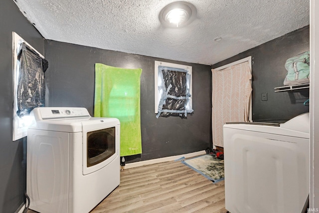 laundry room with light wood-type flooring, a textured ceiling, and independent washer and dryer