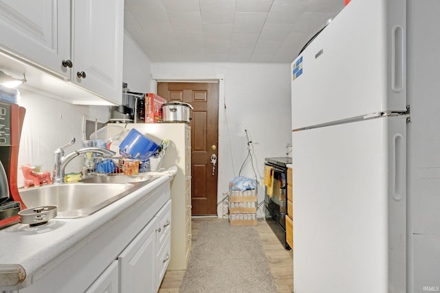 kitchen featuring white cabinets, light wood-type flooring, white fridge, and sink