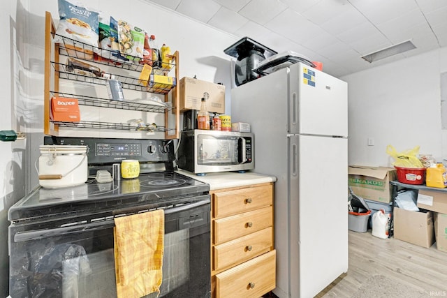 kitchen featuring black range with electric stovetop, light hardwood / wood-style floors, and white refrigerator