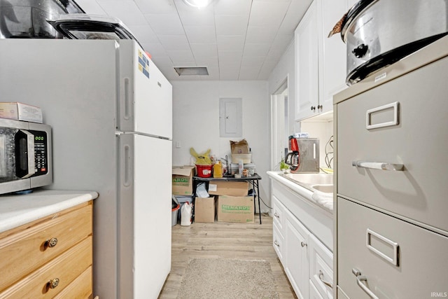 kitchen featuring light hardwood / wood-style floors, white cabinetry, white refrigerator, and electric panel