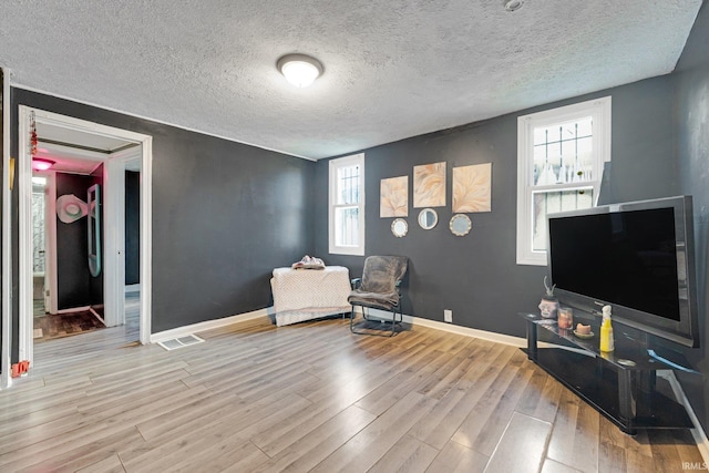 sitting room with a textured ceiling, light hardwood / wood-style floors, and a healthy amount of sunlight