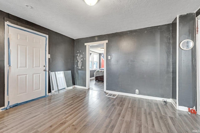 spare room featuring light hardwood / wood-style floors and a textured ceiling