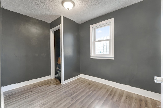 unfurnished room with a textured ceiling and light hardwood / wood-style floors