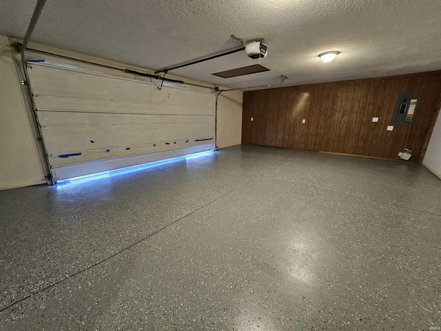 garage featuring electric panel, a garage door opener, and wood walls