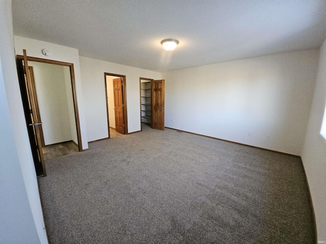 unfurnished bedroom featuring a textured ceiling and dark colored carpet