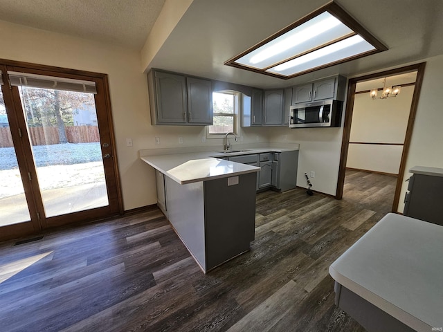 kitchen featuring kitchen peninsula, dark hardwood / wood-style flooring, gray cabinetry, and hanging light fixtures