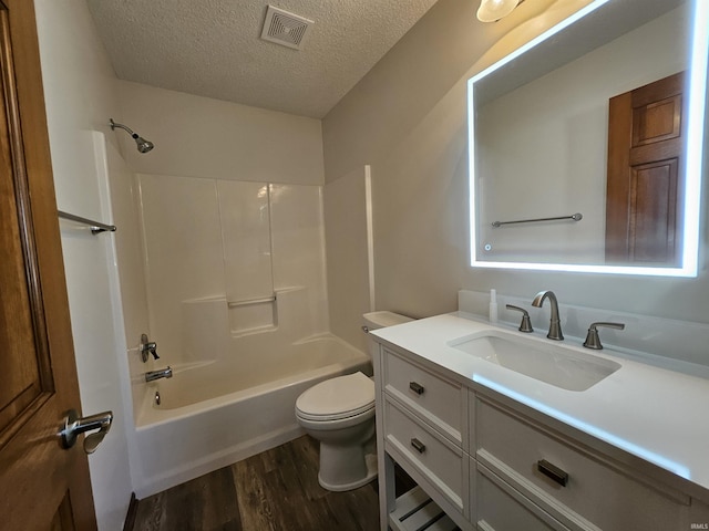 full bathroom with bathtub / shower combination, a textured ceiling, vanity, wood-type flooring, and toilet