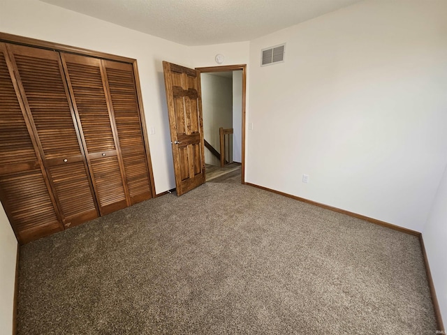 unfurnished bedroom with carpet floors, a textured ceiling, and a closet