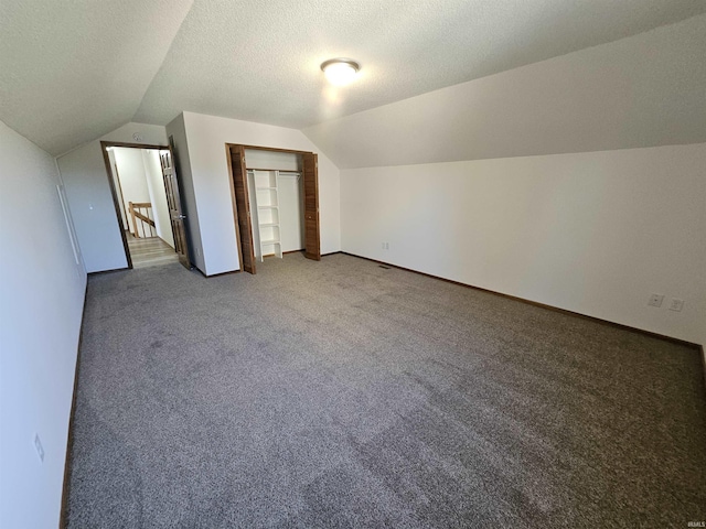 additional living space with a textured ceiling, carpet floors, and lofted ceiling