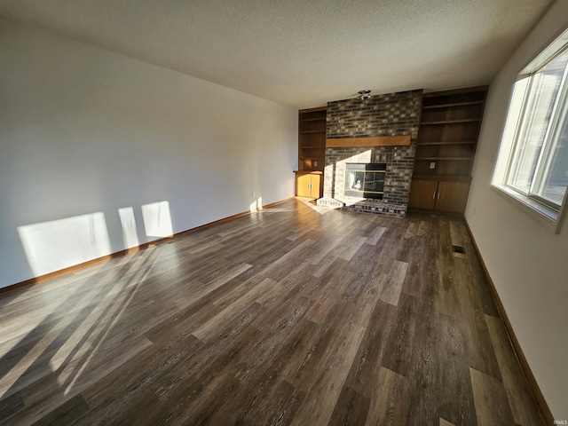 unfurnished living room with a fireplace, dark wood-type flooring, and a textured ceiling