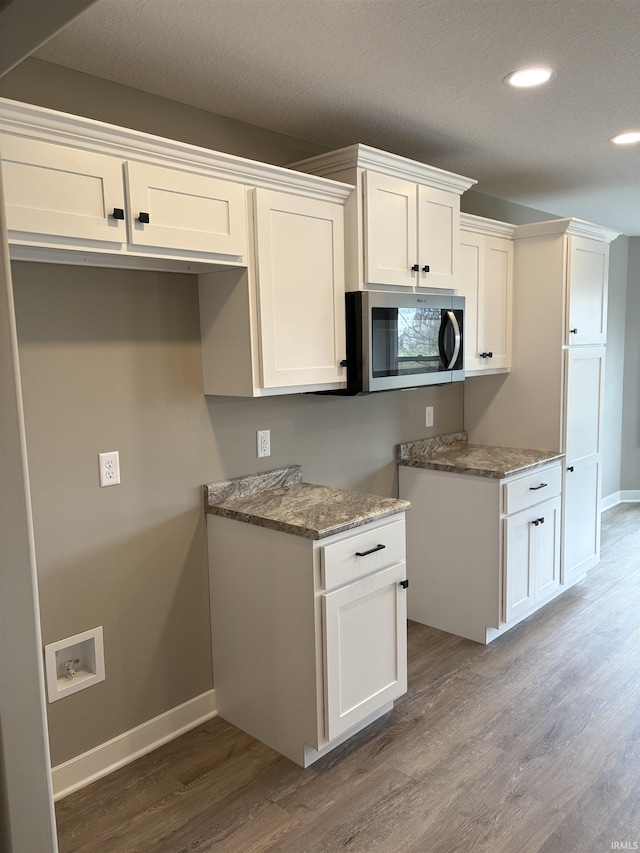 kitchen featuring stainless steel microwave, wood finished floors, white cabinetry, and recessed lighting
