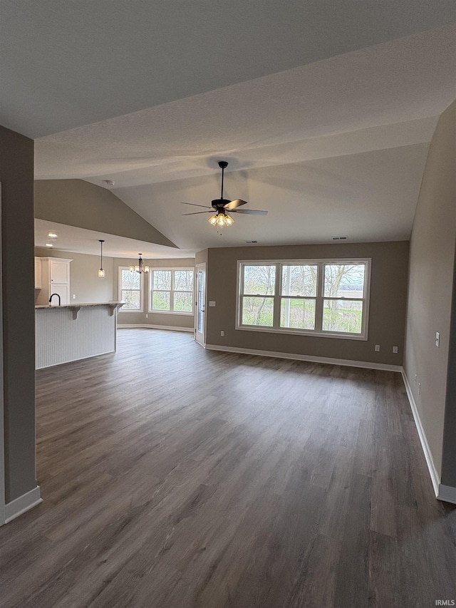 unfurnished living room with lofted ceiling, a wealth of natural light, baseboards, and dark wood-style flooring