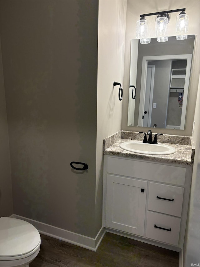 bathroom featuring toilet, vanity, wood finished floors, and baseboards