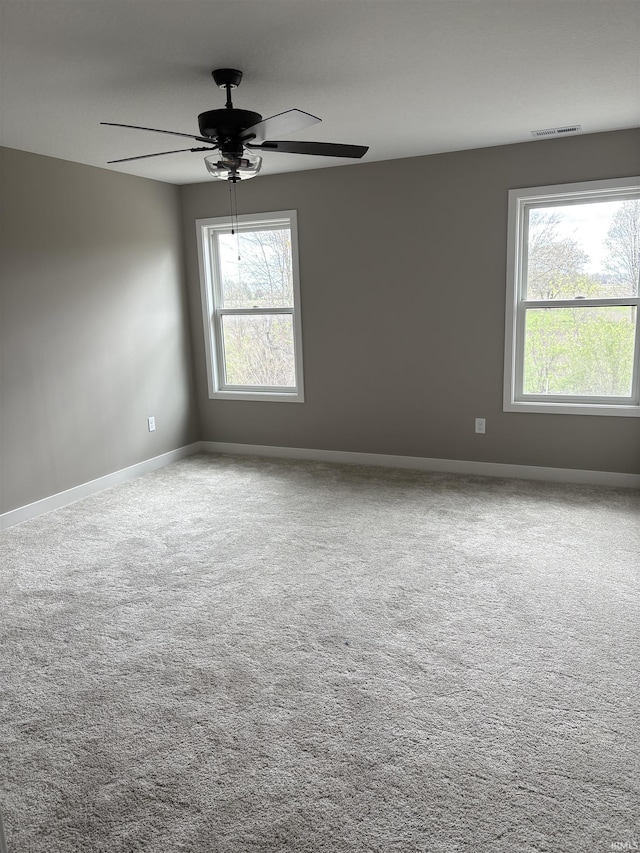carpeted empty room featuring ceiling fan, baseboards, and visible vents
