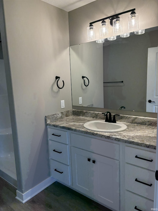 bathroom with baseboards, vanity, and wood finished floors
