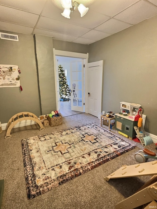 playroom featuring a notable chandelier, a drop ceiling, and french doors