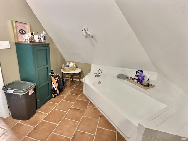 bathroom featuring tile patterned flooring, vaulted ceiling, and a tub