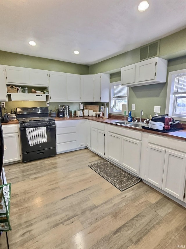 kitchen featuring white cabinets, black range with gas cooktop, and a healthy amount of sunlight