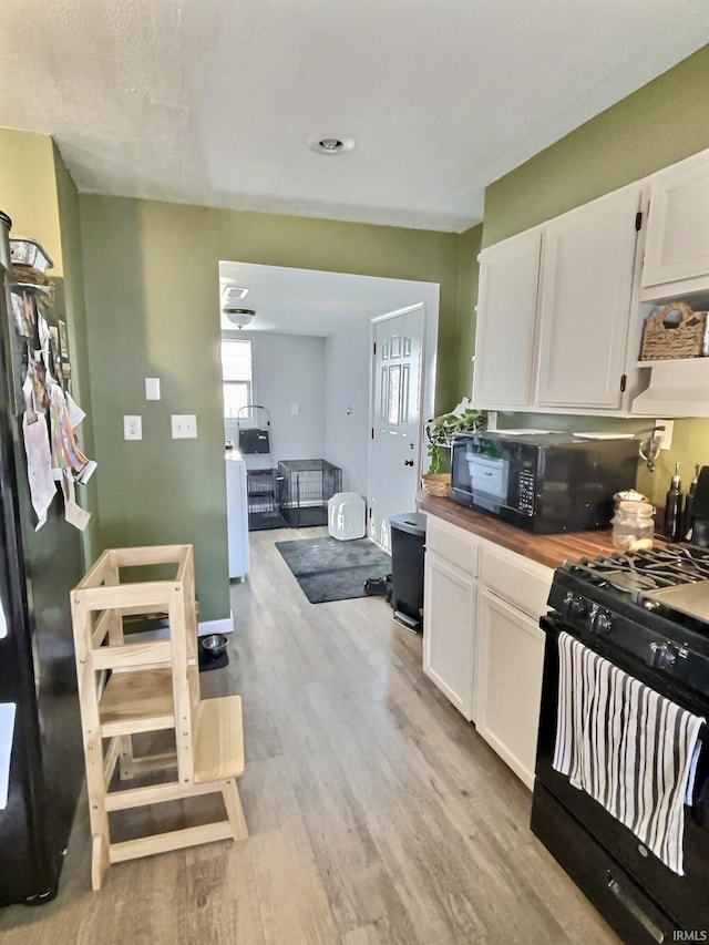 kitchen with white cabinets, light hardwood / wood-style floors, and black appliances