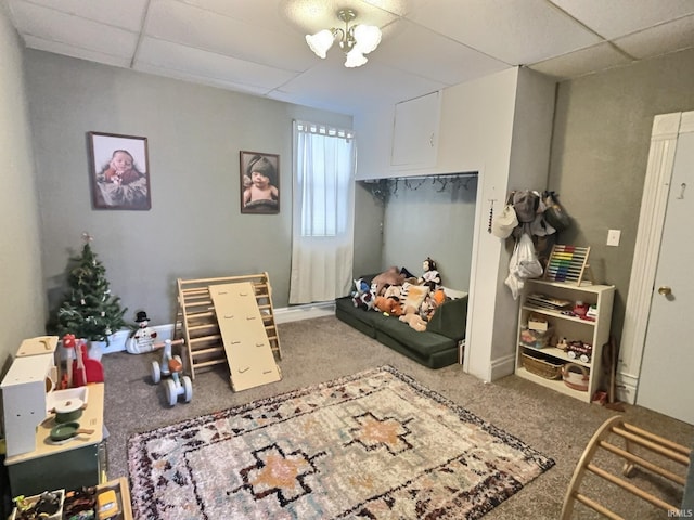 playroom featuring carpet, a paneled ceiling, and a notable chandelier