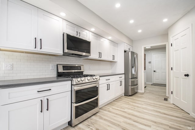 kitchen with backsplash, white cabinetry, light hardwood / wood-style floors, and appliances with stainless steel finishes