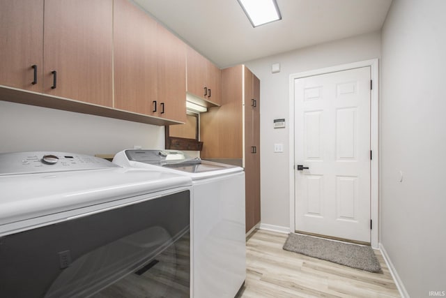 laundry area featuring washing machine and dryer, cabinets, and light wood-type flooring