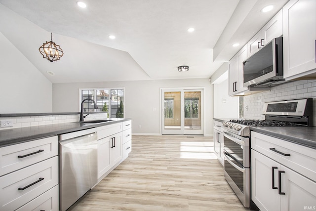 kitchen with white cabinetry, tasteful backsplash, light hardwood / wood-style floors, vaulted ceiling, and appliances with stainless steel finishes