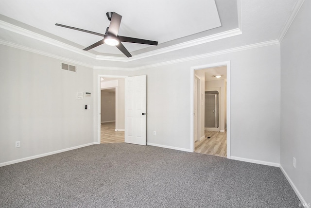 carpeted spare room featuring a tray ceiling, crown molding, and ceiling fan