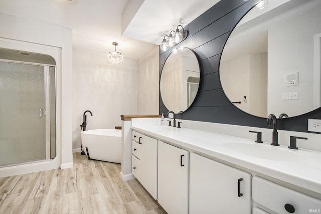 bathroom featuring a chandelier, vanity, wood-type flooring, and shower with separate bathtub