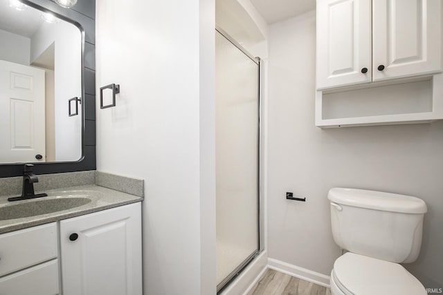 bathroom featuring hardwood / wood-style floors, vanity, toilet, and a shower with shower door