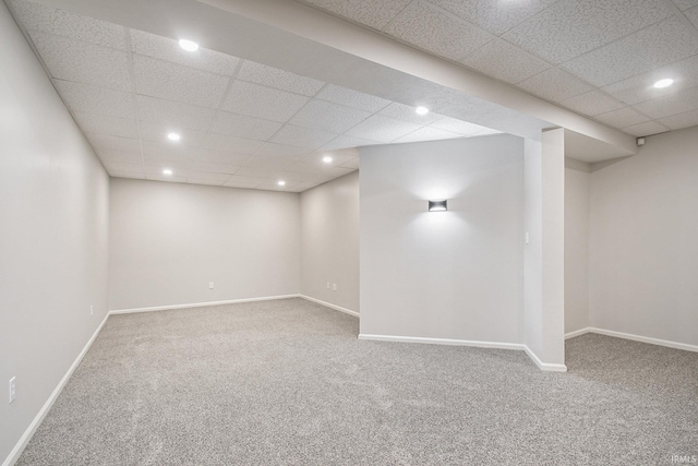 basement with a paneled ceiling and carpet floors