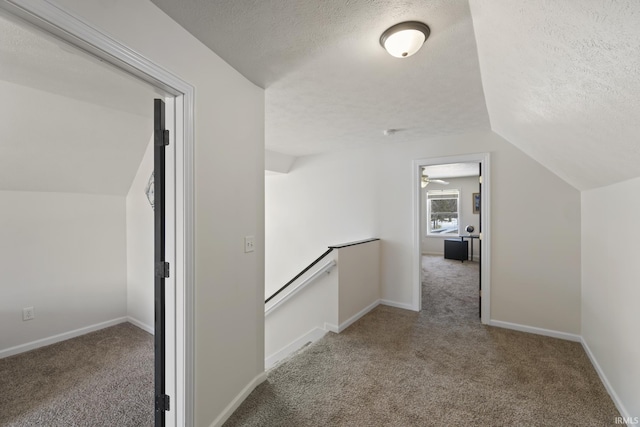 corridor featuring carpet flooring, a textured ceiling, and vaulted ceiling