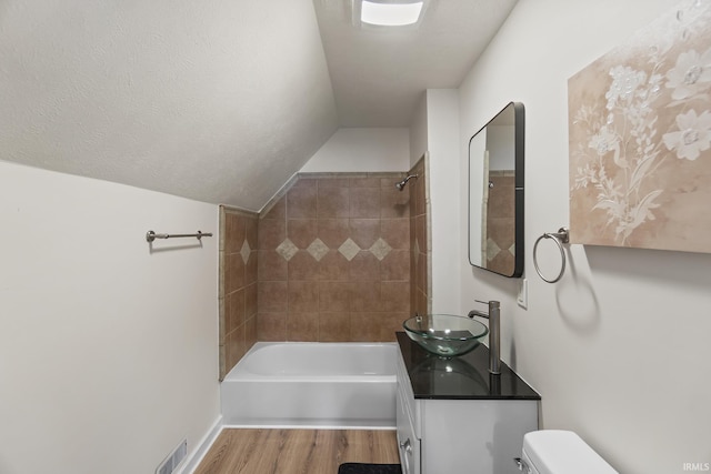 full bathroom with vanity, vaulted ceiling, hardwood / wood-style floors, toilet, and tiled shower / bath