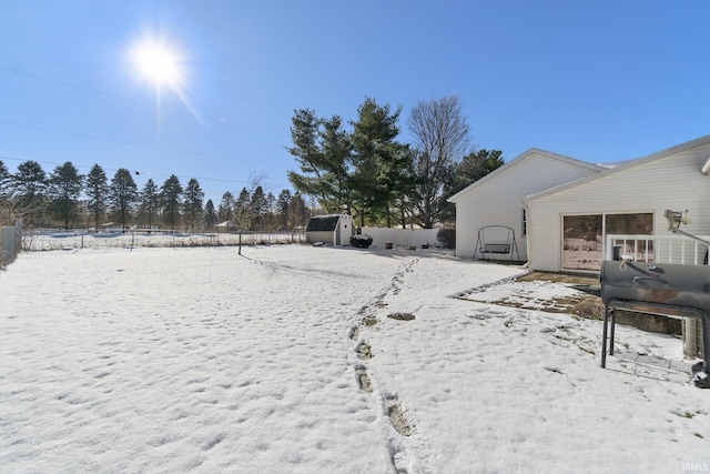 yard covered in snow with a storage shed