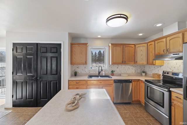 kitchen with sink, dark tile patterned floors, stainless steel appliances, and tasteful backsplash