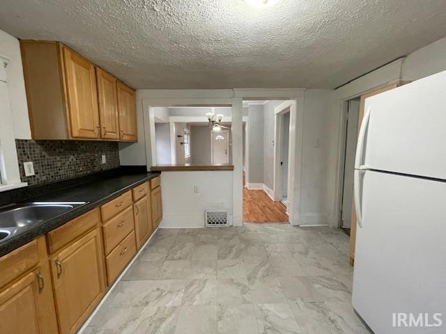 kitchen featuring a textured ceiling, white refrigerator, tasteful backsplash, and ceiling fan