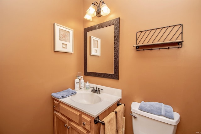 bathroom featuring a notable chandelier, vanity, and toilet